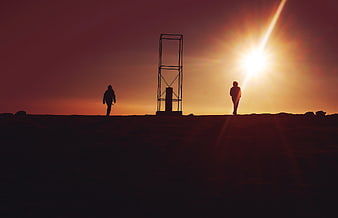 Silhouettes of Two People Walking at Sunset