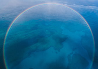 Aerial view of ocean with rainbow halo over shallow reef