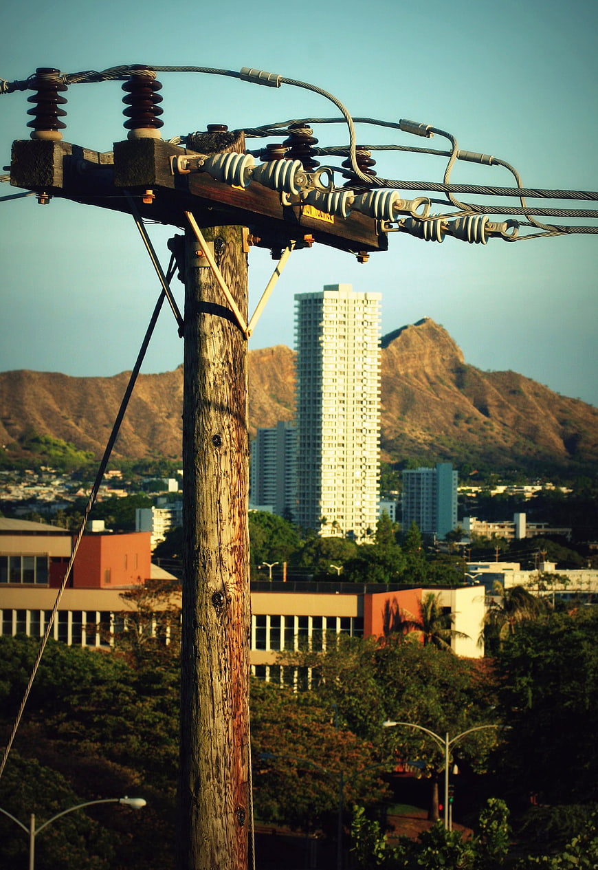Wooden utility pole with power lines against Honolulu skyline and Diamond Head