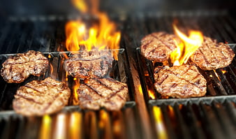 Juicy Burger Patties Sizzling on a Flaming Grill