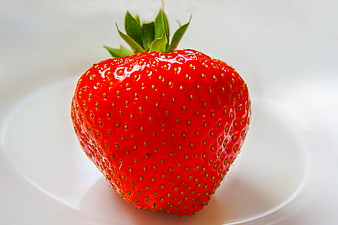 Single Ripe Red Strawberry With Green Leaves On White Plate