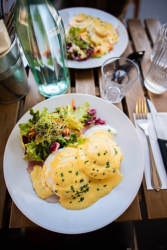 Delicious Eggs Benedict with Salad on Wooden Table