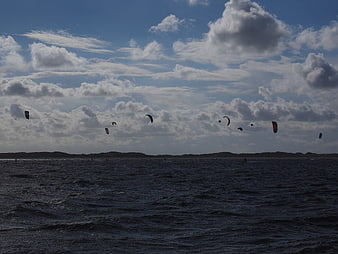 Kitesurfers riding waves under dramatic cloudy sky
