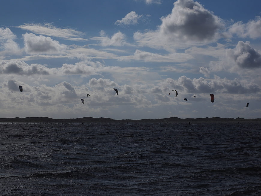 Kitesurfers riding waves under dramatic cloudy sky
