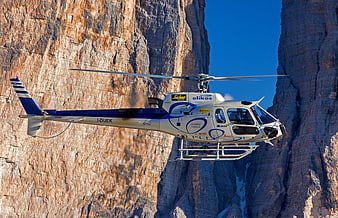 Helicopter flying near steep mountain cliffs