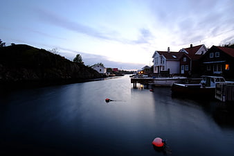 Serene harbor at dusk with calm water and houses