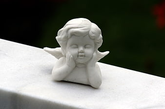 White ceramic angel figurine resting on stone ledge