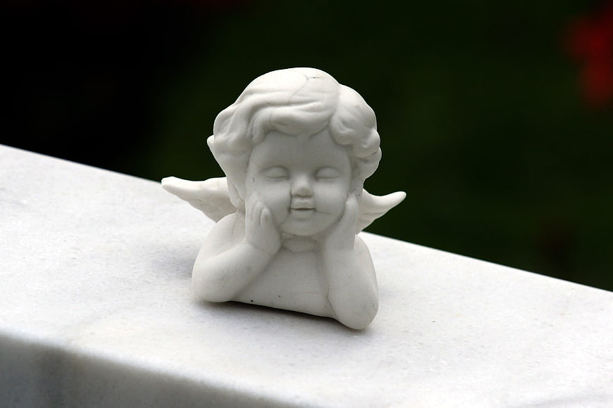 White ceramic angel figurine resting on stone ledge