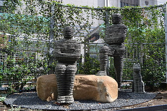Stacked Stone Human and Cat Sculptures in Urban Garden