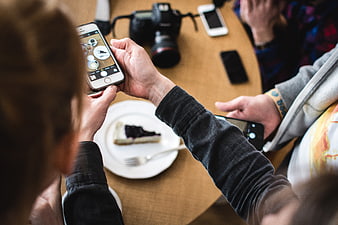 Overhead view of person photographing cake slice with smartphone