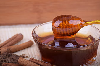 Glass Bowl of Honey with Wooden Dipper and Cinnamon Sticks