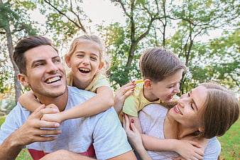 Happy family with children playing piggyback in park