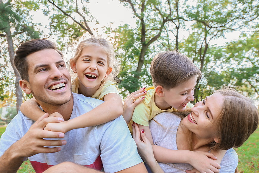 Happy family with children playing piggyback in park