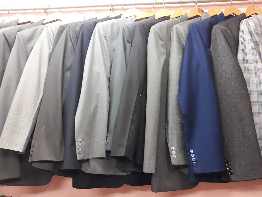 Row of men's suit jackets on hangers in a clothing store