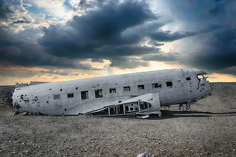 Abandoned Airplane Wreckage In Desert Landscape Under Dramatic Stormy Sky