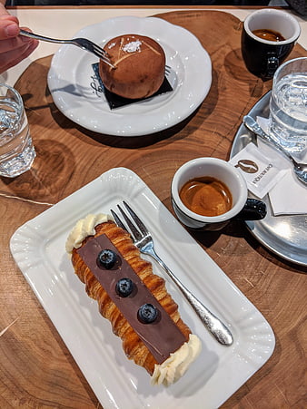 Chocolate croissant and bun with espresso on wooden table