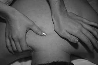 Close-up of hands massaging a person's back in black and white