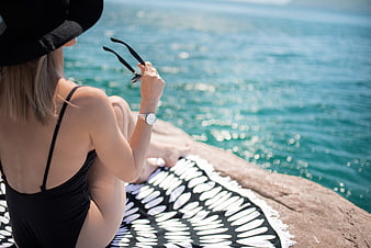 Woman in black swimsuit relaxing by the ocean