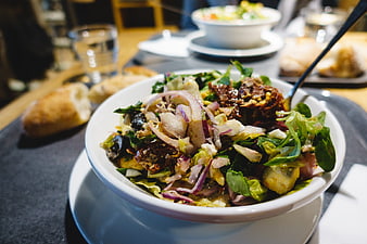 Fresh mixed salad with red onions and dressing in a white bowl