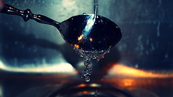 Close-up of water dripping from a shiny metal ladle