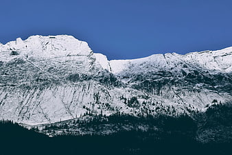 Snow-Covered Mountain Peak Against Deep Blue Sky