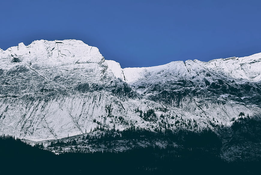 Snow-Covered Mountain Peak Against Deep Blue Sky