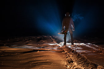 Silhouette of a person holding a chainsaw in a dark snowy landscape