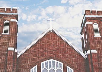 Red Brick Church Facade with White Cross and Blue Sky