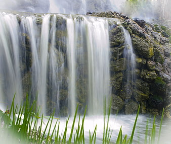 Serene Waterfall Cascading Over Mossy Rocks with Green Grass