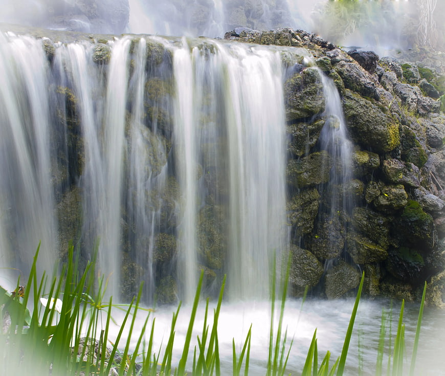 Serene Waterfall Cascading Over Mossy Rocks with Green Grass