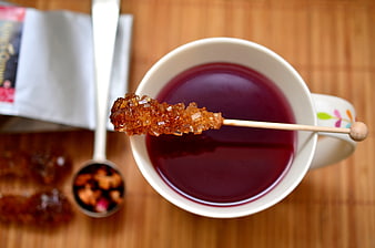 Overhead view of dark fruit tea with a rock sugar stick on a wooden table