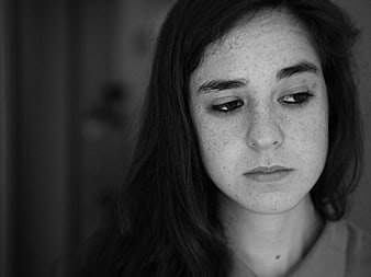Black and white portrait of a young woman with freckles looking down