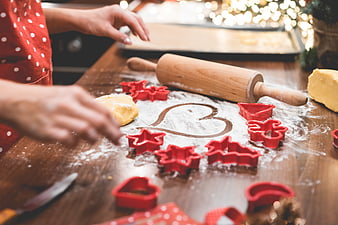 Hands Making Christmas Cookies With Red Cutters And Flour On Wooden Table