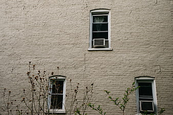 White brick building facade with windows and air conditioners