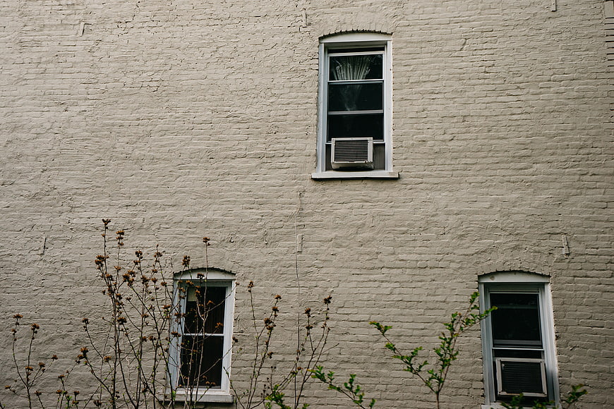 White brick building facade with windows and air conditioners