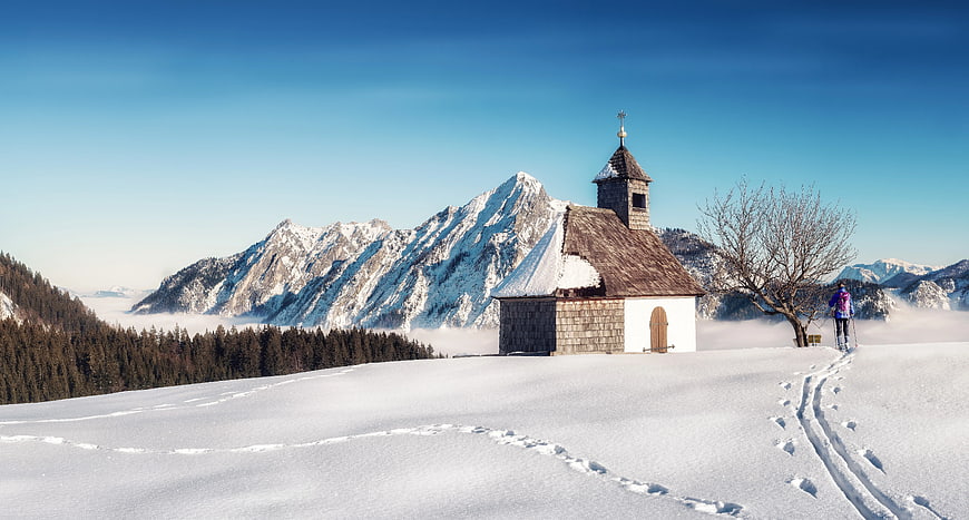 Snowy Mountain Chapel with Hiker and Blue Sky