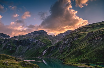 Dramatic mountain landscape with lake and sunset clouds