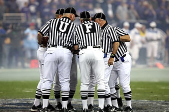 Football referees huddle on field during game