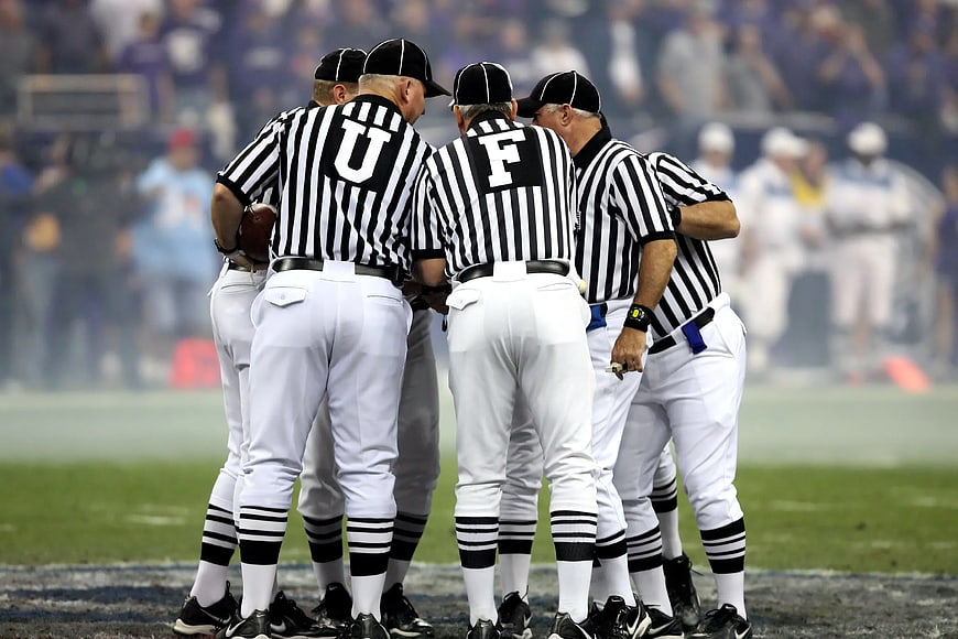 Football referees huddle on field during game
