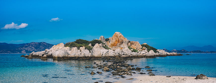 Panoramic view of rocky island in turquoise sea with blue sky