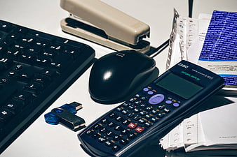 Office desk with calculator, keyboard, mouse, and paperwork