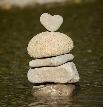 Heart-shaped stone balanced on rock stack in water