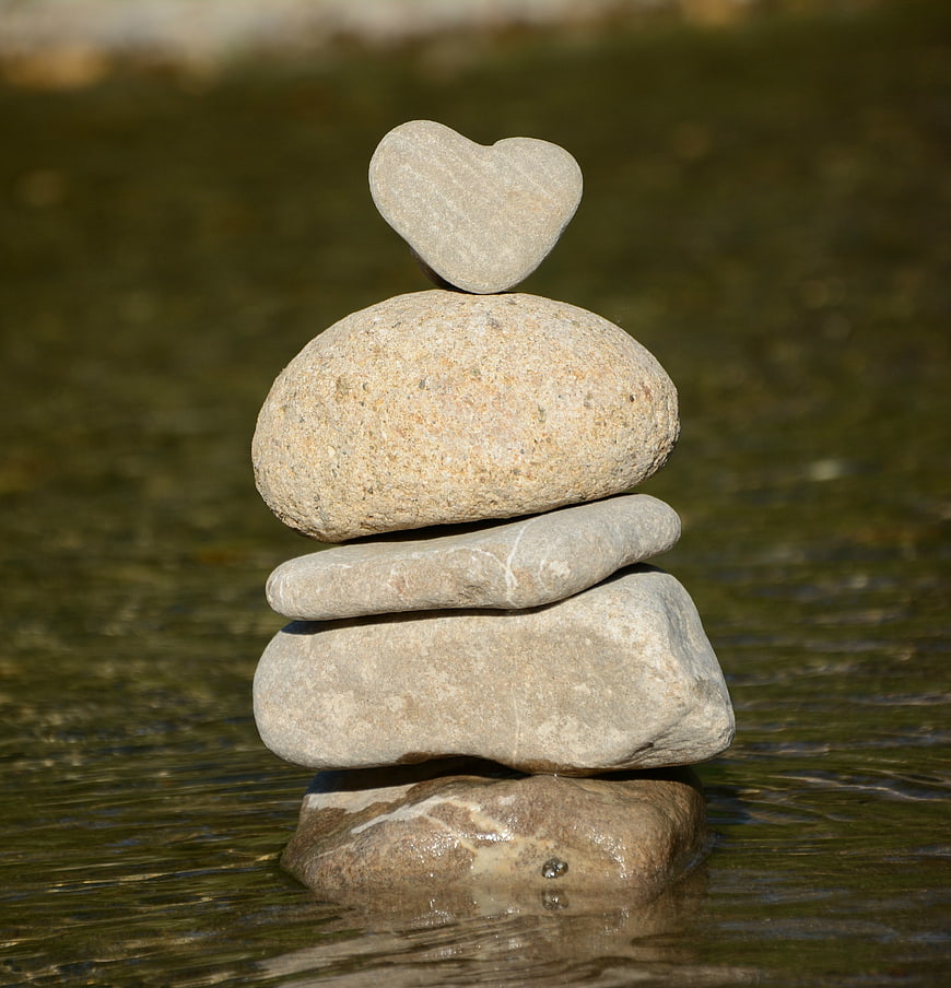 Heart-shaped stone balanced on rock stack in water
