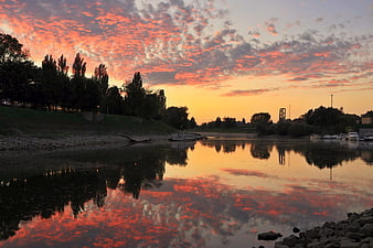 Vibrant Sunset Reflection on River with Boats and Trees