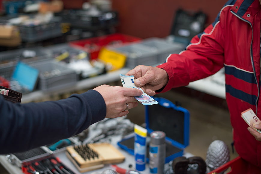 Hands exchanging euro banknotes in a workshop setting