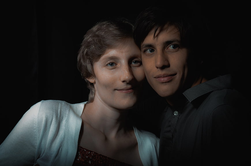Intimate low-key portrait of a smiling couple against black background