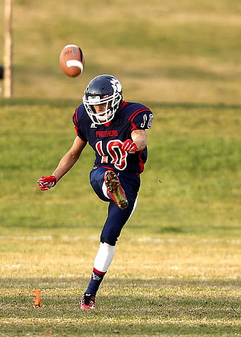 Football Player Kicking Punt on Grass Field