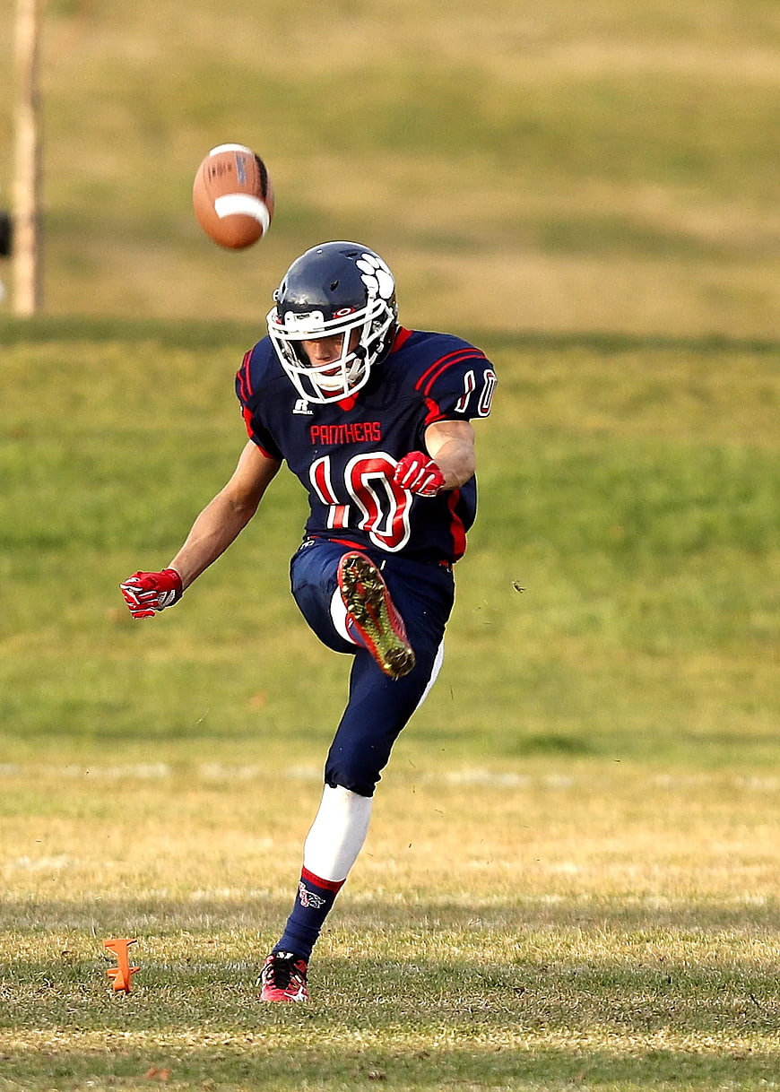 Football Player Kicking Punt on Grass Field