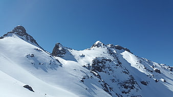 Snow-Covered Alpine Peaks Under Clear Blue Sky