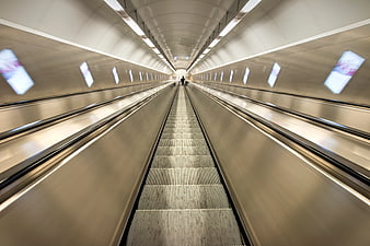 Motion blur escalator tunnel with leading lines and distant figure